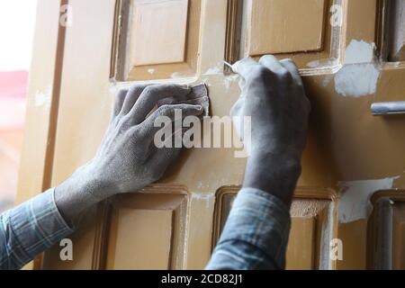 Gros plan des mains de menuisiers en utilisant des ongles et du papier de verre magnifiquement sculpter la porte/la planche en bois sur le lieu de travail, l'artisanat de style indien, la menuiserie. Banque D'Images