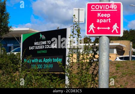 Un panneau pour East Sussex College, campus de Hastings, à côté d'un panneau 'Covid 19 Keep Apart' à Hastings, Sussex, Angleterre, Royaume-Uni. Banque D'Images