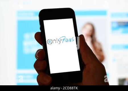 Un homme regardant le site d'OnlyFans sur un ordinateur et téléphone portable Banque D'Images
