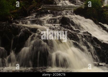 Vue sur les chutes d'Avich, près du Loch Avich, la forêt d'Inverliever, Argyll, en Écosse, montrant la rivière qui coule rapidement au-dessus des rochers déchiquetés Banque D'Images