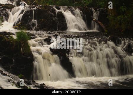 Vue sur les chutes d'Avich, près du Loch Avich, la forêt d'Inverliever, Argyll, en Écosse, montrant la rivière qui coule rapidement au-dessus des rochers déchiquetés Banque D'Images