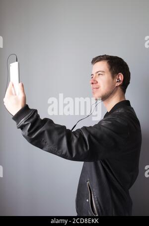 Jeune homme qui fait un appel vidéo avec son téléphone mobile et écouteurs Banque D'Images