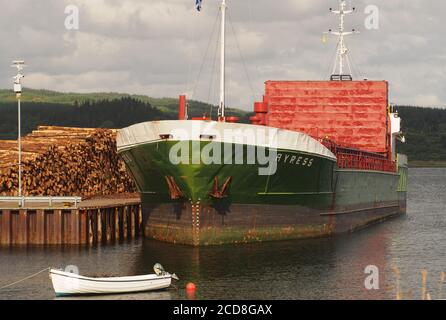 Un grand navire en bois, MV Ayress, amarré à l'embarcadère d'Ardrishaig attendant d'être chargé avec des rondins avec un petit bateau à ramer en premier plan Banque D'Images