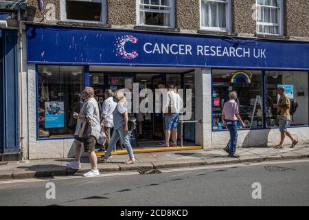 Piétons à l'extérieur d'une succursale de cancer Research UK à Totnes, Devon, Angleterre, Royaume-Uni Banque D'Images