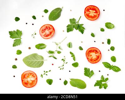 Tomates, herbes et feuilles de basilic isolées sur fond blanc. Vue de dessus. Banque D'Images