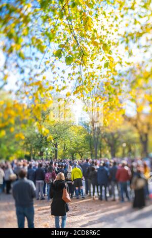Les gens regardent les performances de la rue sous les couleurs d'automne des arbres dedans Central Park Banque D'Images