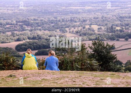 Deux femmes s'assoient sur une colline et regardent la campagne de Surrey Hills depuis l'arrière, Angleterre, Royaume-Uni, août 2020 Banque D'Images