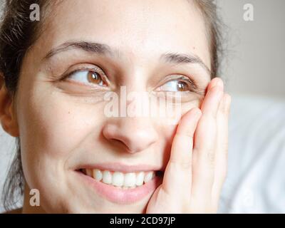 Jeune femme latine souriant avec la main sur son visage regardant de côté