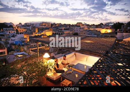 Maroc, région de Tanger Tetouan, Tanger, hôtel Dar Nour, couple sur un banc de la terrasse de la maison d'hôtes Dar Nour donnant sur la kasbah à la tombée de la nuit Banque D'Images
