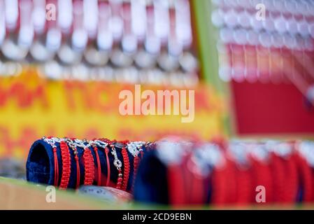 Vente de bijoux bon marché, bracelets en fils rouges et éléments métalliques. Banque D'Images