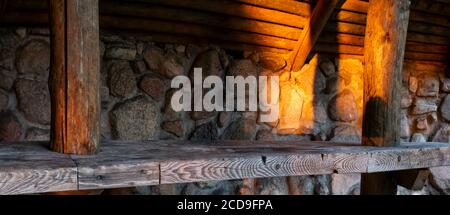 table en bois sur le fond d'un mur en pierre éclairé par la lumière naturelle et chaude du soleil couchant Banque D'Images