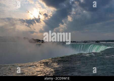 Niagara Falls Horseshoe Falls avec des rayons de soleil de début de matinée à travers le ciel couvert Banque D'Images