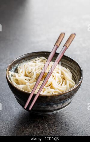 Nouilles udon cuites. Nouilles japonaises traditionnelles dans un bol sur table noire. Banque D'Images