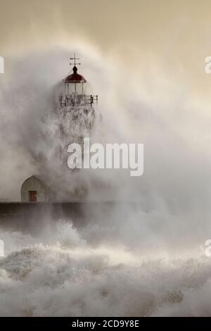 Vieux phare à l'embouchure du Douro pendant la tempête en mer au coucher du soleil. Banque D'Images