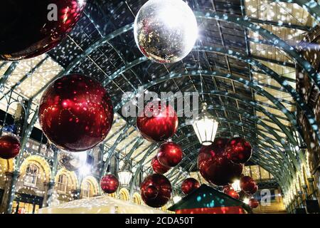 Les décorations de Noël illuminent la nuit à Covent Garden Londres Angleterre Royaume-Uni pendant la période des fêtes de fin d'année qui est un populaire destination touristique Banque D'Images