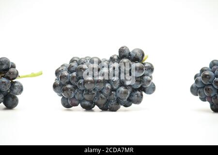 Petit groupe isolé de raisins techniques foncés couché sur son côté sur fond blanc Banque D'Images