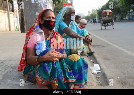 Les populations pauvres du Bangladesh attendent des secours du côté de route pendant un confinement imposé par le gouvernement comme mesure préventive contre Le COVID-19 coronav Banque D'Images