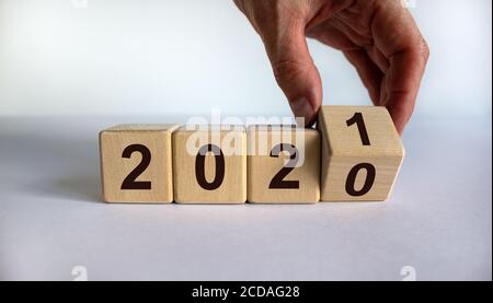 La main tourne un cube et change l'année '2020' en '2021'. Magnifique fond blanc. Copier l'espace. Banque D'Images