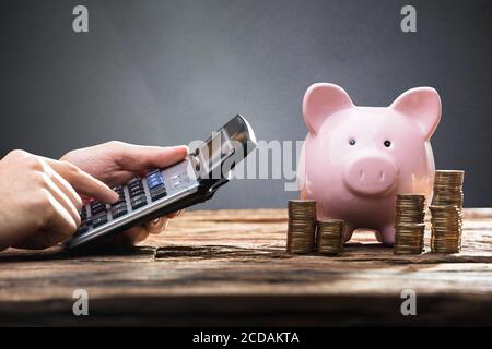 Pile et calculatrice de budget d'argent de Piggybank. Homme travaillant Banque D'Images