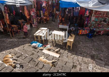 Un homme construit des meubles dans le marché extérieur en face de la chapelle de Calvary à Chichicatenango, au Guatemala, tandis que les chiens dorment sur les marches de l'église. Banque D'Images