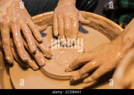 gros plan des mains d'une femme et d'un enfant argile dans un atelier de poterie Banque D'Images