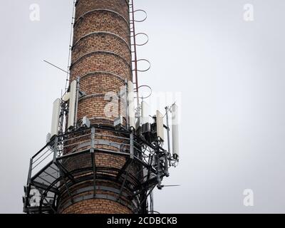 Station de base de téléphonie mobile, sur une vieille cheminée industrielle en brique équipée d'antenne 3G, 4G et 5G, au sommet d'un bâtiment européen, utilisée pour le cellulaire Banque D'Images