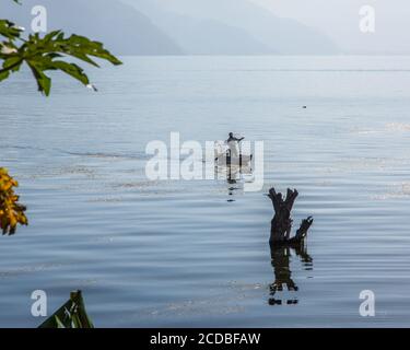 Un pêcheur maya avec son fishtrap en fil dans son cayuco ou canoë sur le lac Atitlan par San Pedro la Laguna, Guatemala. Les eaux de lac montantes depuis 2009 ont Banque D'Images