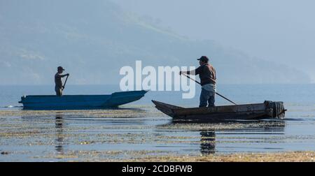 Deux pêcheurs mayas pagagent leurs cayucos ou canoës sur le lac Atitlan par San Pedro la Laguna, Guatemala. Banque D'Images