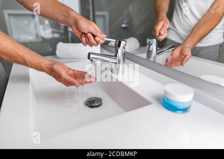 Eau chaude courante de la salle de bains évier robinet homme vérifiant la pression et la température se lave les mains dans un style de vie moderne Banque D'Images