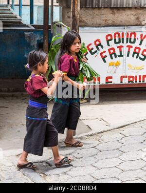 Deux jeunes filles maya Cakchiquel portant une robe traditionnelle s'accrochonner dans la rue de la petite ville de Santa Cruz la Laguna, Guatemala. Banque D'Images