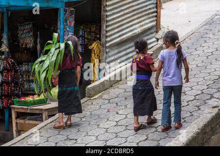 Trois jeunes filles maya Cakchiquel portant une robe traditionnelle s'accrochée à la rue dans la petite ville de Santa Cruz la Laguna, Guatemala. Banque D'Images