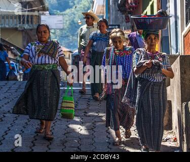 Tzutujil femmes mayas et un homme en robe traditionnelle dans une rue à Santiago Atitlan, Guatemala. Il porte le mi-genou à rayures traditionnel Banque D'Images