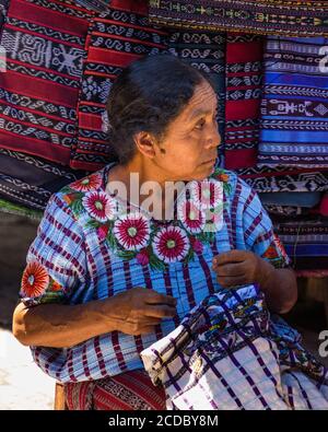 Une femme maya Tzutujil plus ancienne en robe traditionnelle brodeuses à main un chemisier tissé de huipil à vendre dans le marché ouvert hebdomadaire à Santiago Atitlan, Guate Banque D'Images