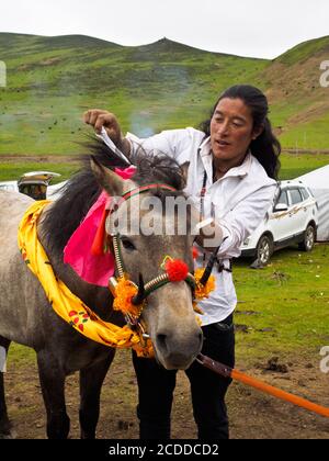 Le cavalier Khampa préparait son cheval pour la course dans un festival de chevaux près de Litang City. Banque D'Images