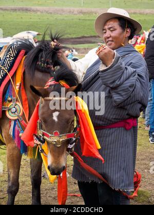 Le cavalier Khampa préparait son cheval pour la course dans un festival de chevaux près de Litang City. Banque D'Images