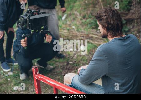 Derrière la scène. L'acteur en face de la caméra sur le plateau extérieur. Scène de film de groupe Banque D'Images