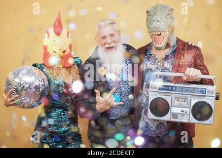 Les gens dansant à la fête du carnaval portant un t-rex et un masque de poulet. Des amis qui ont plaisir à écouter de la musique avec une vieille chaîne stéréo - drôle de tendance concept - Focus sur f Banque D'Images
