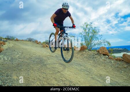 Cycliste en t-shirt violet équitation un VTT. Un homme sur le sentier en vélo tout-terrain lors d'une journée de tempête. Concept sport extrême - image Banque D'Images