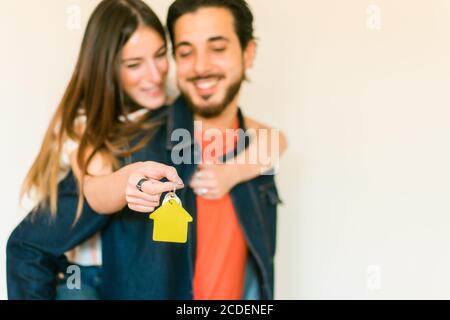 Heureux couple dans le nouvel appartement . La femme a la clé d'une maison. Clé avec porte-clés en forme de maison. Mise au point sur la main - image Banque D'Images