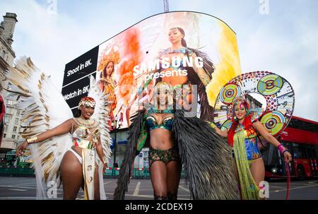 Un trio de danseuses antillaises soca, Donna Cupid-Thuesday, Andrea Wallace et Fiona Compton, divertissent des passants tandis que Samsung dévoile sur le Piccadilly Circus une bande-annonce pour le tout premier Digital Notting Hill Carnival, Londres. Banque D'Images