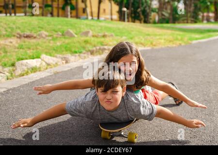 Frère et sœur jouant avec le skateboard. Un petit garçon et une petite fille sur la planche à roulettes dans le parc. Jeune en été. Concept de famille et d'enfance. Banque D'Images