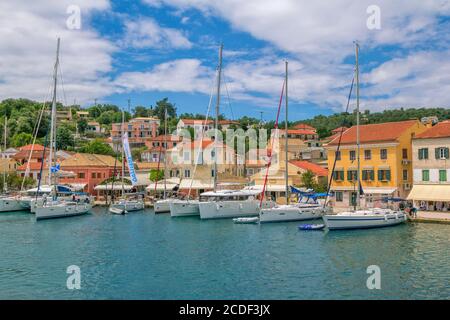 Ile de Paxos/Grèce- 7 mai 2019: Vue sur le magnifique port de Loggos – baie de mer avec l'eau turquoise calme, les navires et les yachts vieilles maisons colorées, ciel bleu Banque D'Images