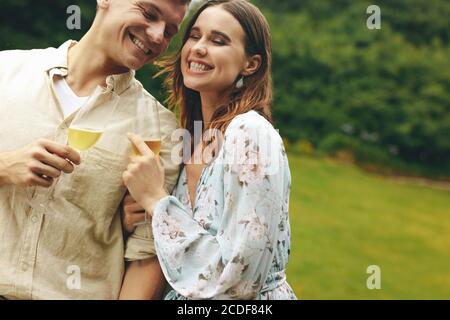 Couple au parc avec champagne. Jeune homme et femme aimant au parc avec des verres à champagne. Banque D'Images