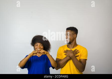 Mignon jeune couple africain souriant et montrant des gestes d'amour avec mains Banque D'Images