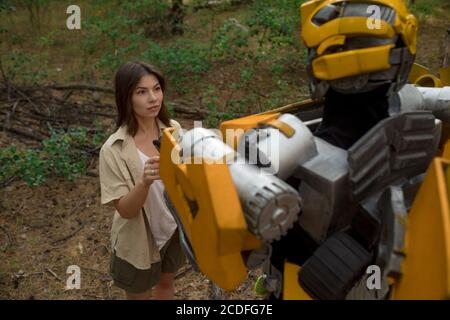 Cosplayer à l'image d'un robot transformateur et fille se tiennent ensemble parmi la forêt. Gros plan. Banque D'Images