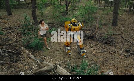 Cosplayer à l'image d'un robot transformateur et fille courir ensemble parmi la forêt. Banque D'Images