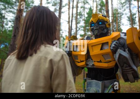 Cosplayer à l'image d'un robot transformateur et fille se tiennent ensemble parmi la forêt. Gros plan. Banque D'Images