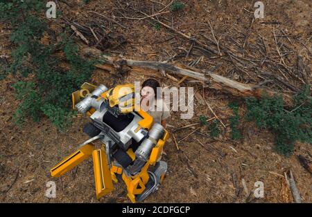 Cosplayer à l'image d'un robot transformateur et fille se tiennent ensemble parmi la forêt. Vue de dessus. Banque D'Images