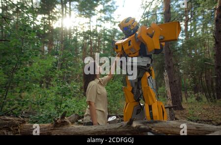 Cosplayer à l'image d'un robot transformateur et fille se tiennent ensemble parmi la forêt. Banque D'Images