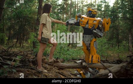 Cosplayer à l'image d'un robot transformateur et fille se tiennent ensemble parmi la forêt. Banque D'Images